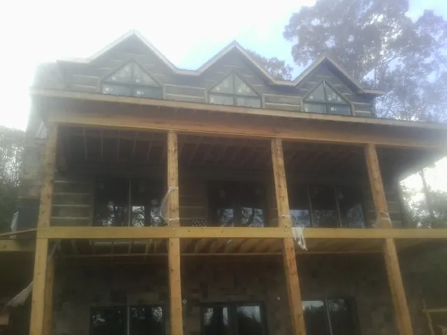 Dormers and porch framing on a large log home under construction — Roof Coating work by our crew in San Marcos