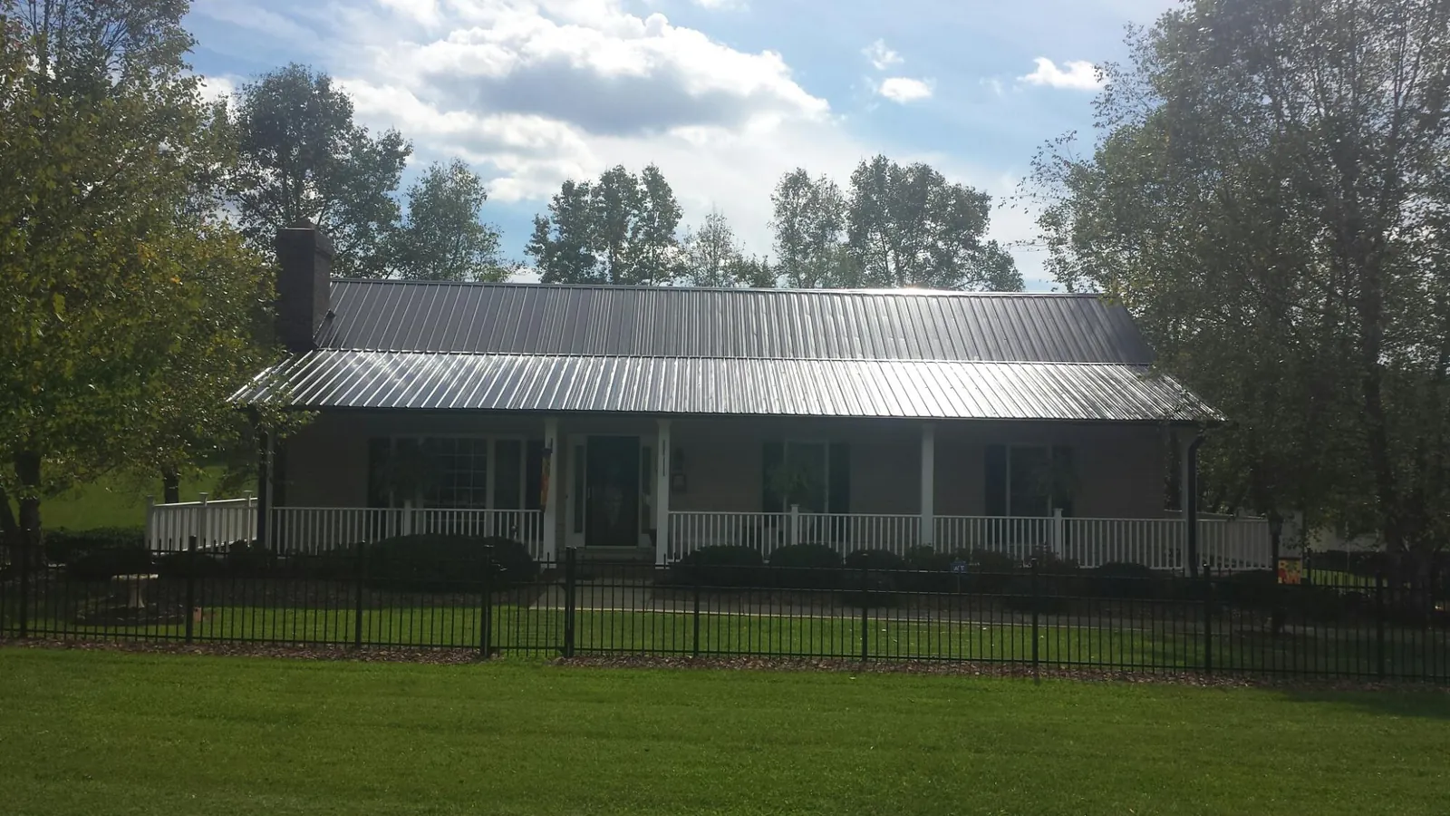 Gray metal roof on a brick ranch with a full width front porch — Gutter Guard Installation work by our crew in San Marcos